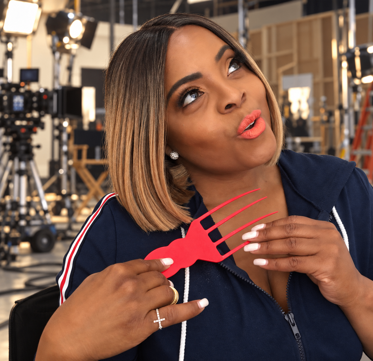 Brand ambassador Dr. Brely Evans holding the red Luxe Therapy Scalp Soother on a film set